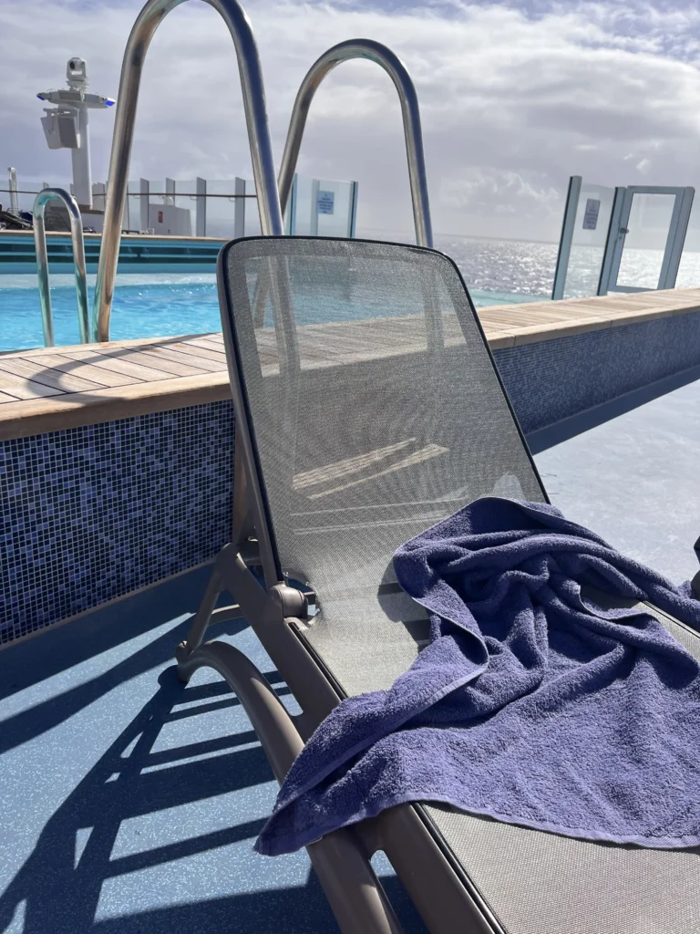 Empty sun lounger beside the pool aboard P&O Arvia after a towel was blown away