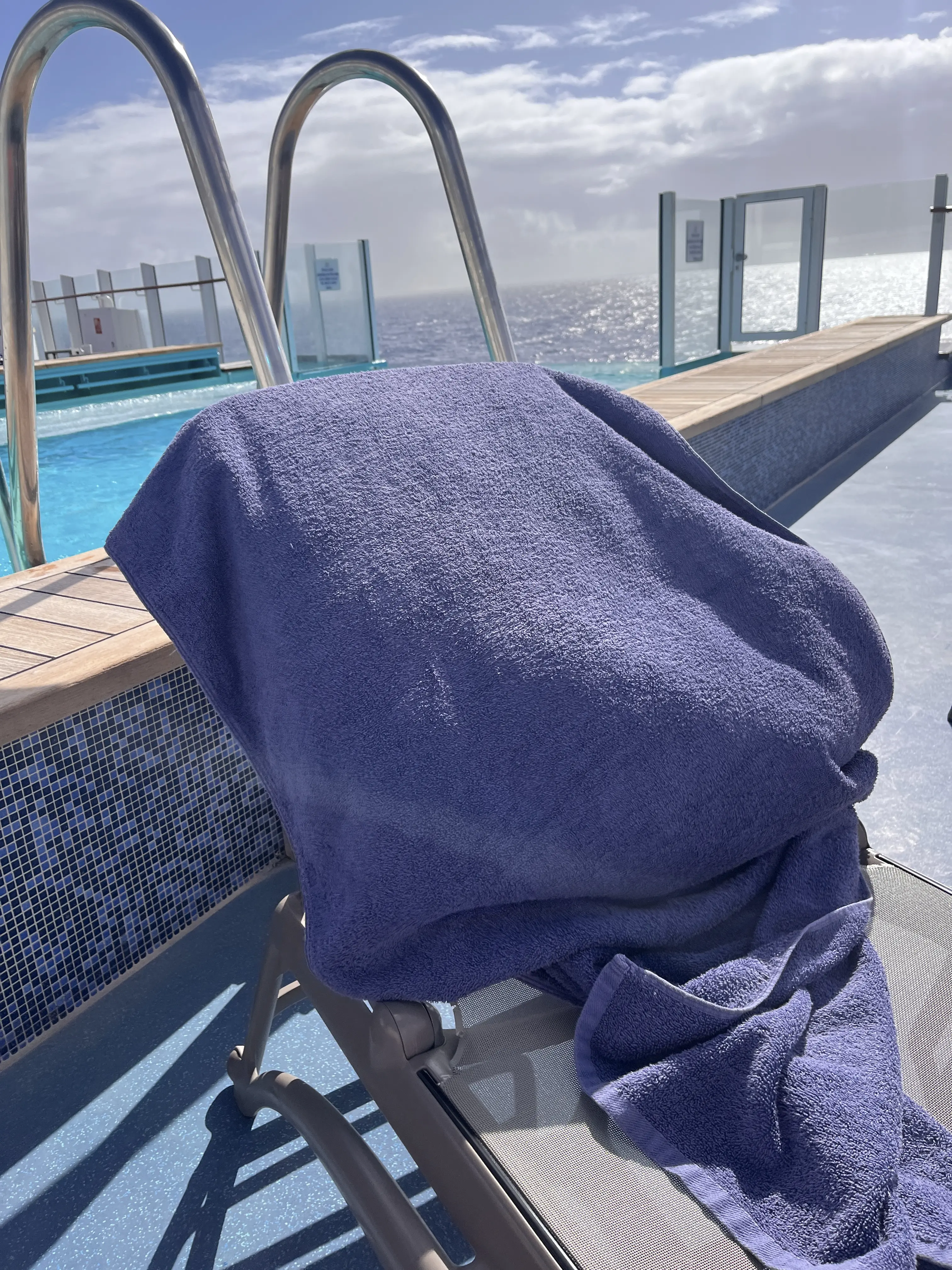 Blue towel displaced by strong wind on a sun lounger beside the pool aboard P&O Arvia