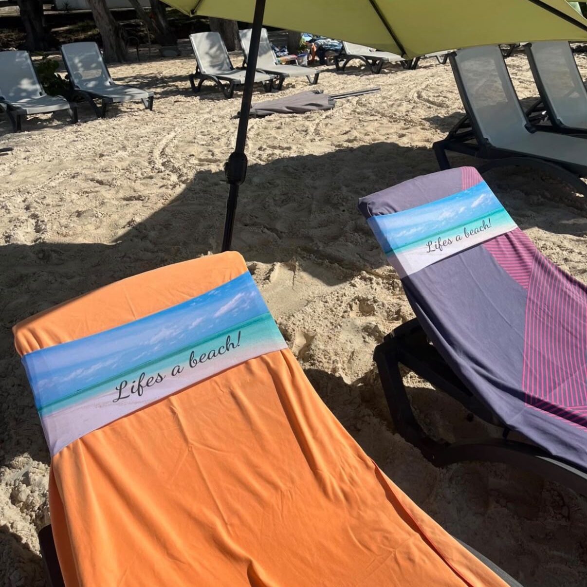 Two Life’s a Beach tcboo sun lounger towel bands securing towels on a sandy beach