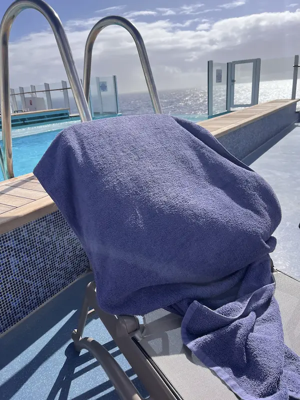 Blue towel displaced by strong wind on a sun lounger beside the pool aboard P&O Arvia